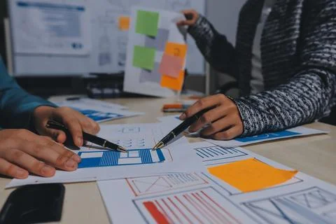 Group of young application developers analyzing uxui mobile app templates d.. Stock Photos