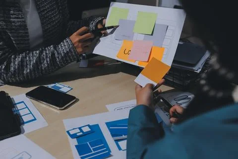 Group of young application developers analyzing uxui mobile app templates d.. Stock Photos