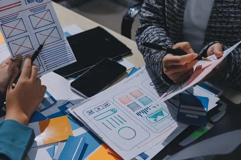 Group of young application developers analyzing uxui mobile app templates d.. Stock Photos