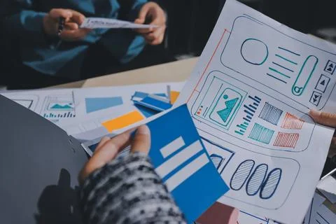 Group of young application developers analyzing uxui mobile app templates d.. Stock Photos