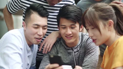 Group of young asian adults looking at cellphone together Stock Footage 149542166