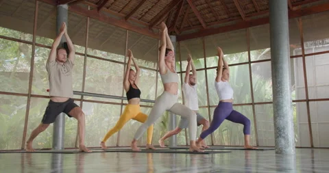 Group of young caucasian practicing yoga warrior pose together. Stock Footage 154444366