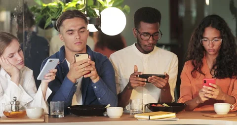 Group of young concentrated people looking at phone screen while sitting in cafe Stock Footage 138094565