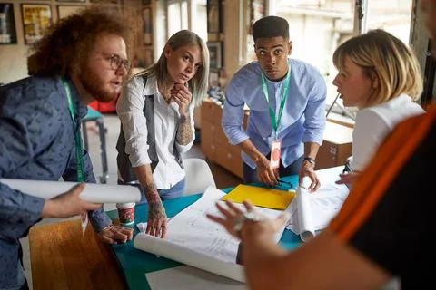 A group of young creative colleagues in the office is discussing about projec Stock Photos