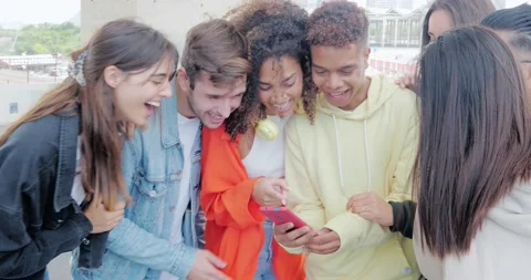 Group of young diverse smiling millennial friends looking at a mobile phone Stock Footage 230284664