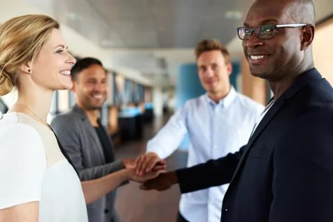 Group of young executives smiling with hands together showing team camaraderi Stock Photos