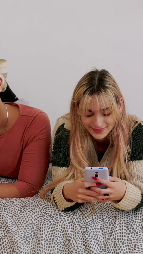 Group of young female friends browsing smart phones relaxing on bed Stock Footage 346256275