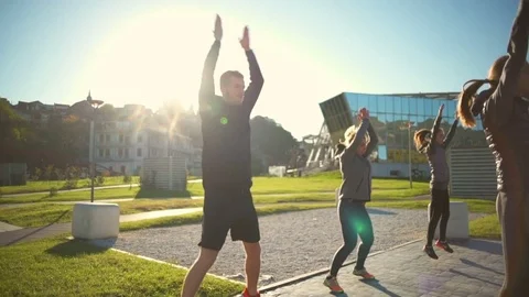 A group of young friends doing jumping jacks outdoors synchronously closeup Stock Footage 70966642
