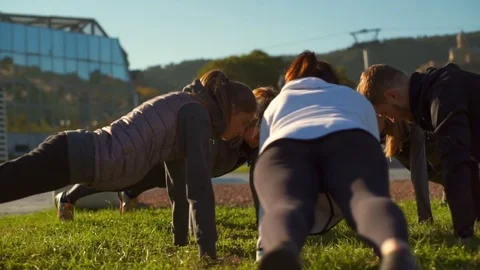 A group of young friends doing the plank exercise on the grass slow motion Stock Footage 70966899