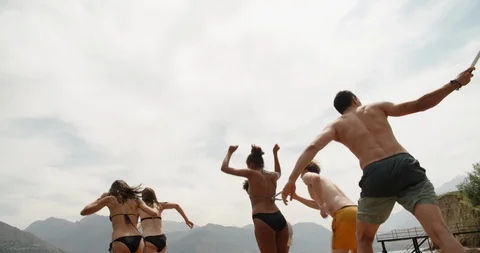 Group of young friends jumping from pier into lake, enjoying their holiday Stock Footage