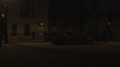 Group of young friends sitting in a circle on a city street at night Stock Footage 342567191