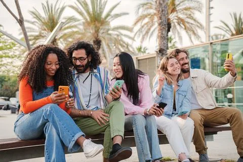 Group of young friends using the smartphone to browse on internet, take selfies Stock Photos