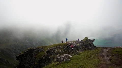 Group of young friends walking along on the edge of a cliff Video stock 126002170