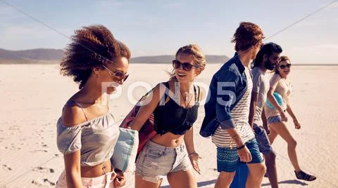 Group of young friends walking down a beach Stock-Fotos