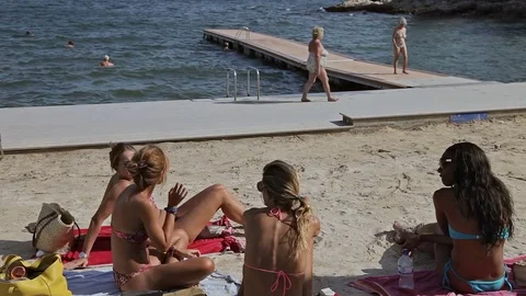 A group of young girls in a bikini sunbathing on the beach. Spanish in a Stock Footage 77143145