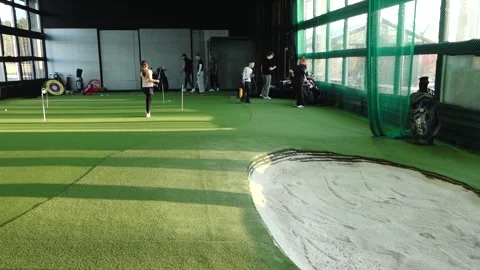 Group of young golfers practicing putting drills indoors on artificial turf Stock Footage 332133822