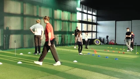 Group of young golfers practicing putting drills indoors on artificial turf Stock Footage 332409620