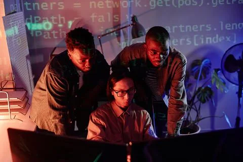 Group of young intercultural programmers bending in front of computer monitors Stock-Fotos