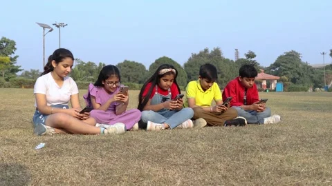 Group of young kids using smartphone together at summer park, concept of sc.. Vidéo 329091735