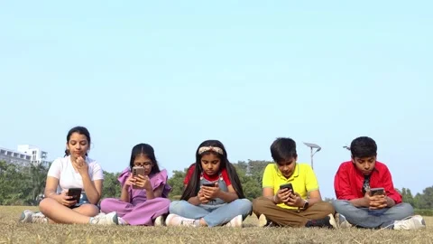Group of young kids using smartphone together at summer park, concept of sc.. 動画素材 329091747