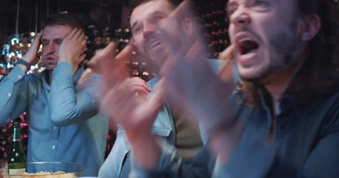 Group of young men hang out in bar, watching game on TV and supporting sports Stock Footage 190541585