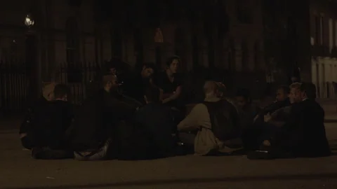 Group of young men sitting in a circle on street at night Stock Footage 342567460