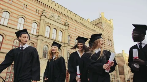 Group of young multi ethnical graduates in traditional black gowns and caps Stock Footage 83602828