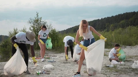 Group of young multi-race people cleaning up the beach at lake on cloudy day Video stock 114290899