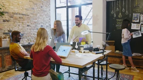Group of Young Multiethnic Designers Smiling and Discussing Ideas in Office Stock Footage 115443076