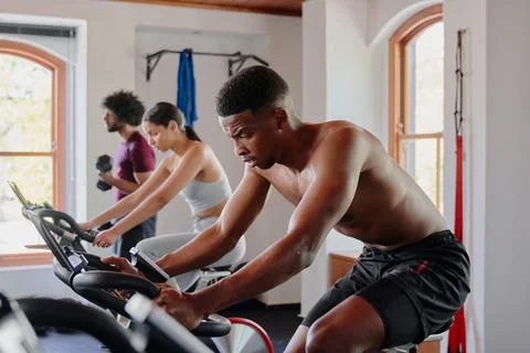 Group of young multiracial adults doing cardio on exercise bike at the gym Stock Photos