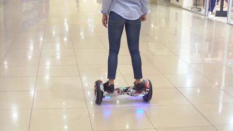Group of young people are moving around the shopping center on a hyroscooter Stock Footage 76563698