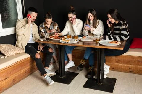 A group of young people are using their cell phones in a pizzeria Stock Photos