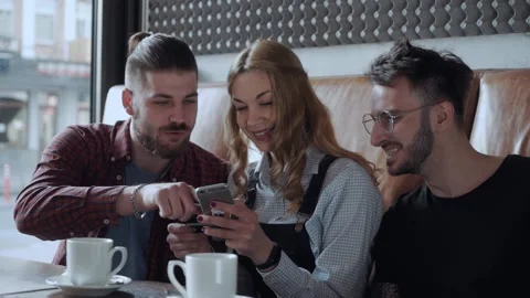 Group of young people at the cafe making purchase online, disuccing it and Stock Footage 158794414