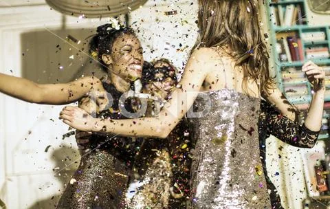 Group of young people celebrating at a party with falling confetti. Stock Photos