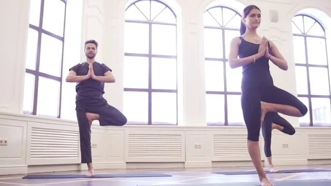 Group of young people doing yoga tree pose in the class with windows Stock Footage 76182517