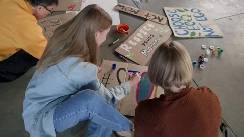 A group of young people draw posters and protest against environmental pollution Stock Footage 233220101