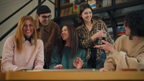 Group of young people engaging in conversation and fun activities at a library d 動画素材 337325822