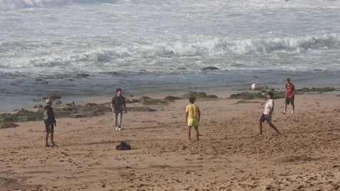 A group of young people playing Keepie uppie juggling with a ball on a sandy Stock Footage 336536751