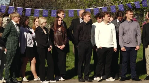Group of young people posing outdoors beneath European Union flag bunting Stock Footage 335169911