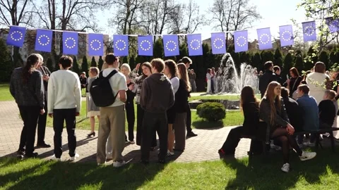 Group of young people posing outdoors beneath European Union flag bunting Stock Footage 335171639