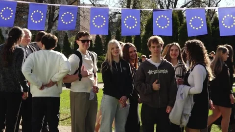 Group of young people posing outdoors beneath European Union flag bunting Stock Footage 335171945