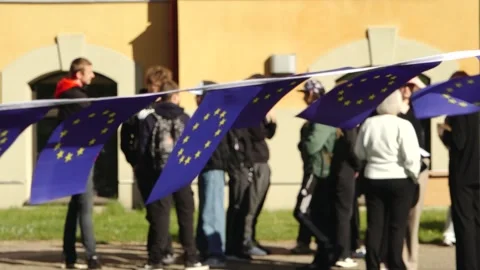 Group of young people posing outdoors beneath European Union flag bunting Stock Footage 335172460