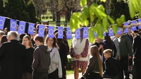Group of young people posing outdoors beneath European Union flag bunting Stock Footage 335174551