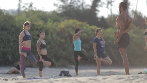 Group of young people practice yoga outdoors in rays of dawn Stock Footage 73918062