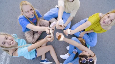Group of young people sitting on the parking lot and enjoying ice creams, tog Stock Footage 150288530