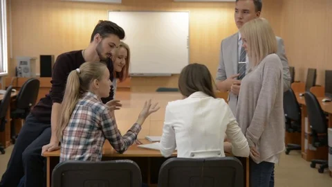Group of young people sitting at a table solve a problem. Stock Footage 80849482