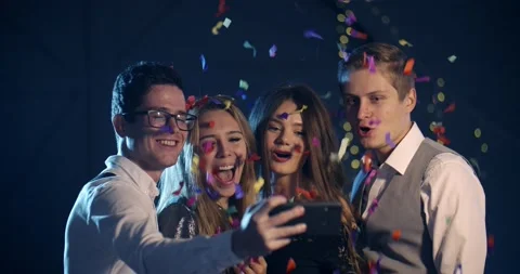 A group of young people smiling and throwing confetti, taking selfies for the Vídeo Stock 142738958