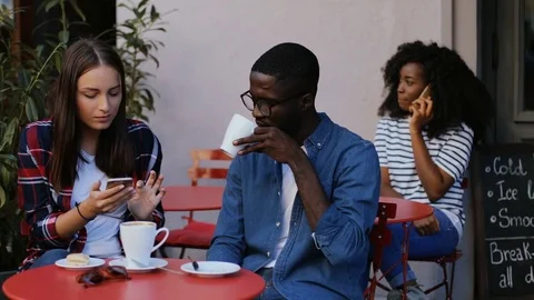 Group of young people spending time on terrace in cafe. Handsome man drinking Stock Footage 81836035