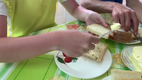 A group of young people at the table spread butter at breakfast close-up Stock Footage 157473563