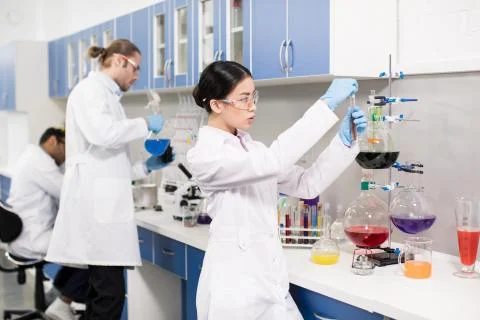 Group of young professional scientists making experiment in research laborato Fotos Stock
